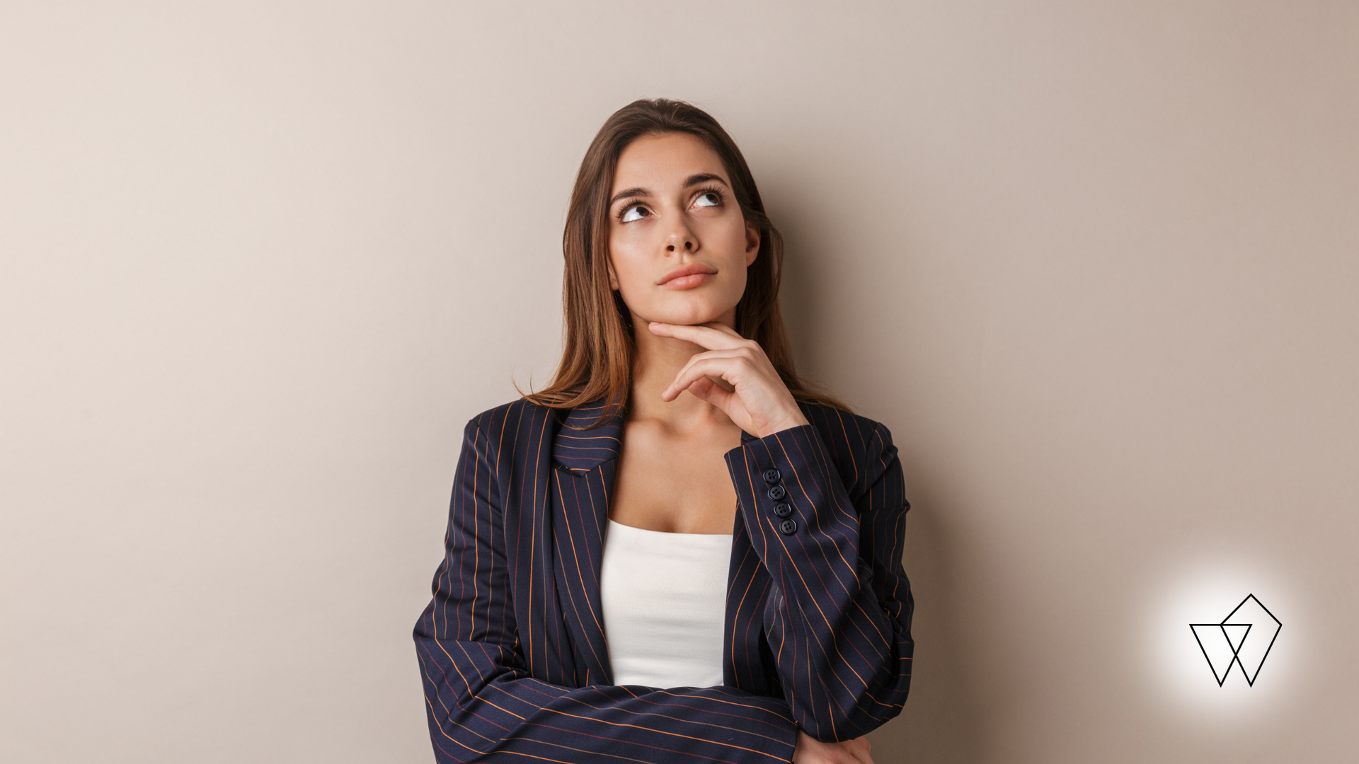 Woman in a dark blazer and white top thinking against a plain beige background