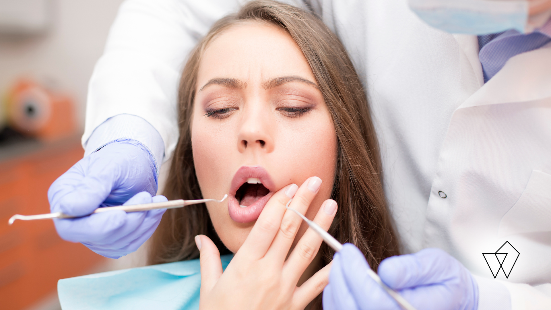 Dentist examining a patient’s open mouth with dental tools and gloved hands