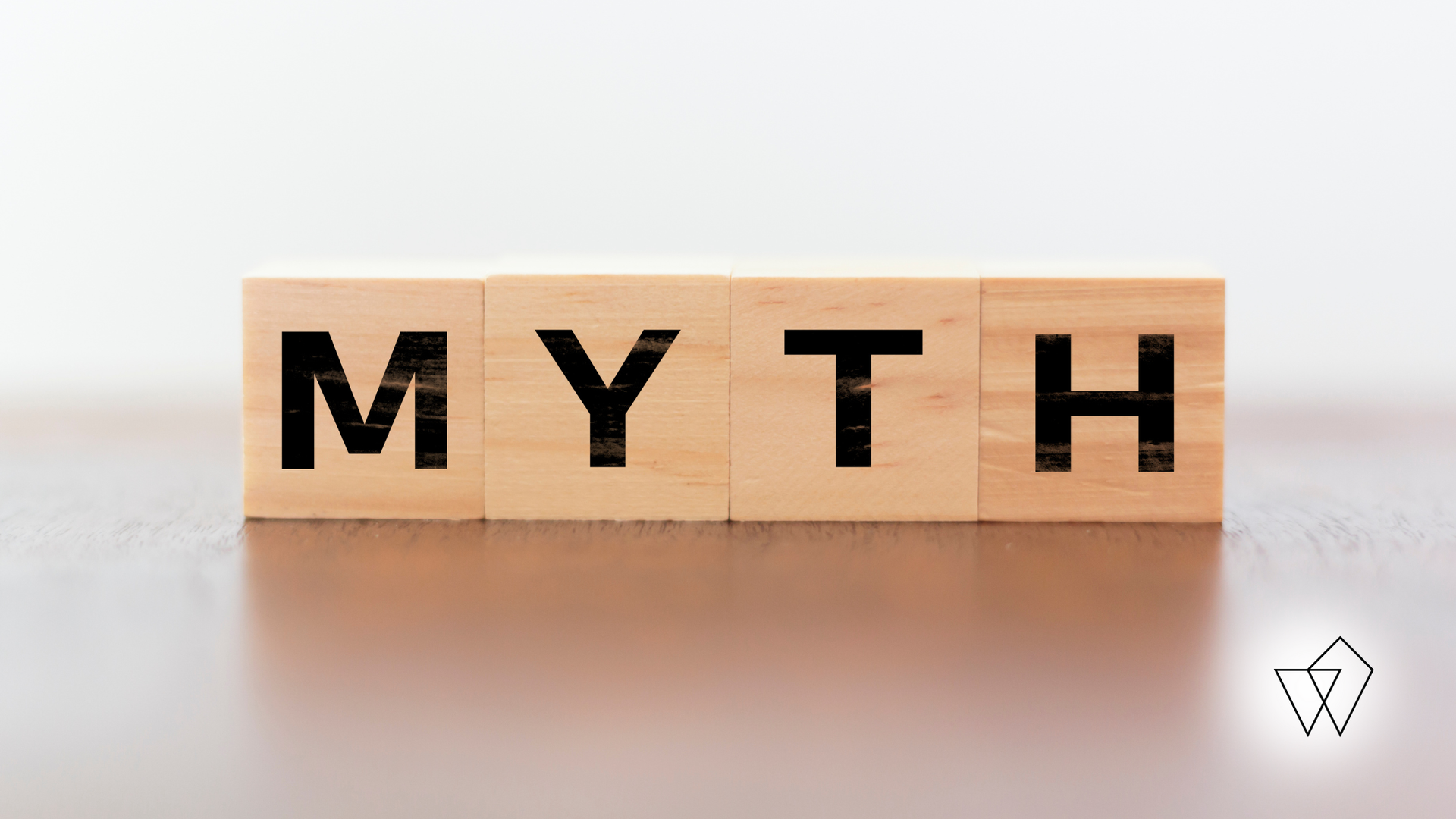 Wooden blocks spelling “MYTH” on a white background.