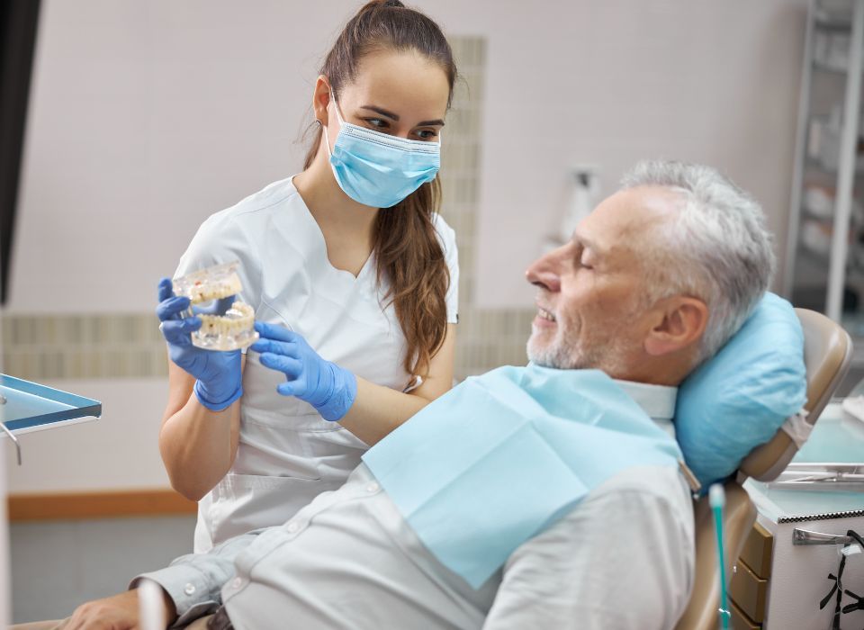 Dentist showing a dental model to a patient in a dental chair.