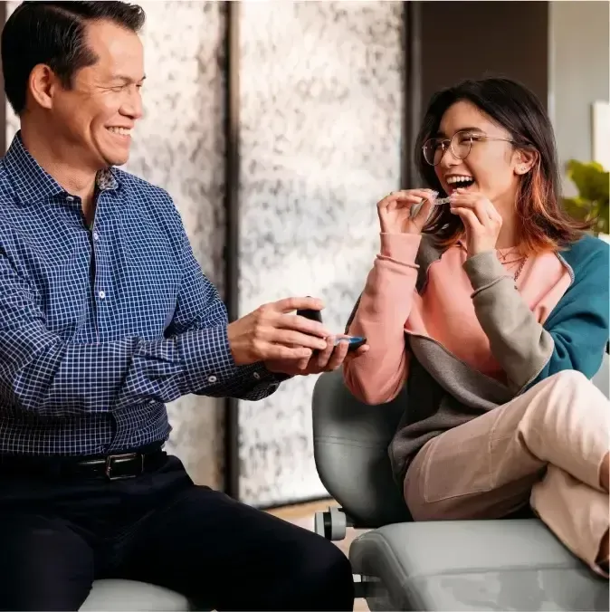 Dentist showing a dental implant model to a patient in an office setting.