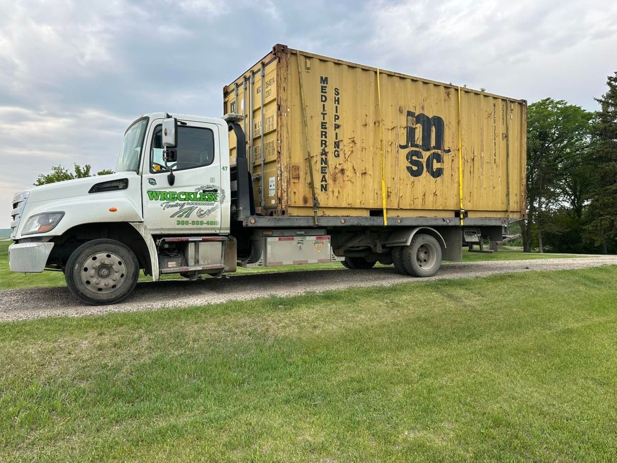 White box truck with yellow MSC shipping container on a grassy roadside under cloudy skies