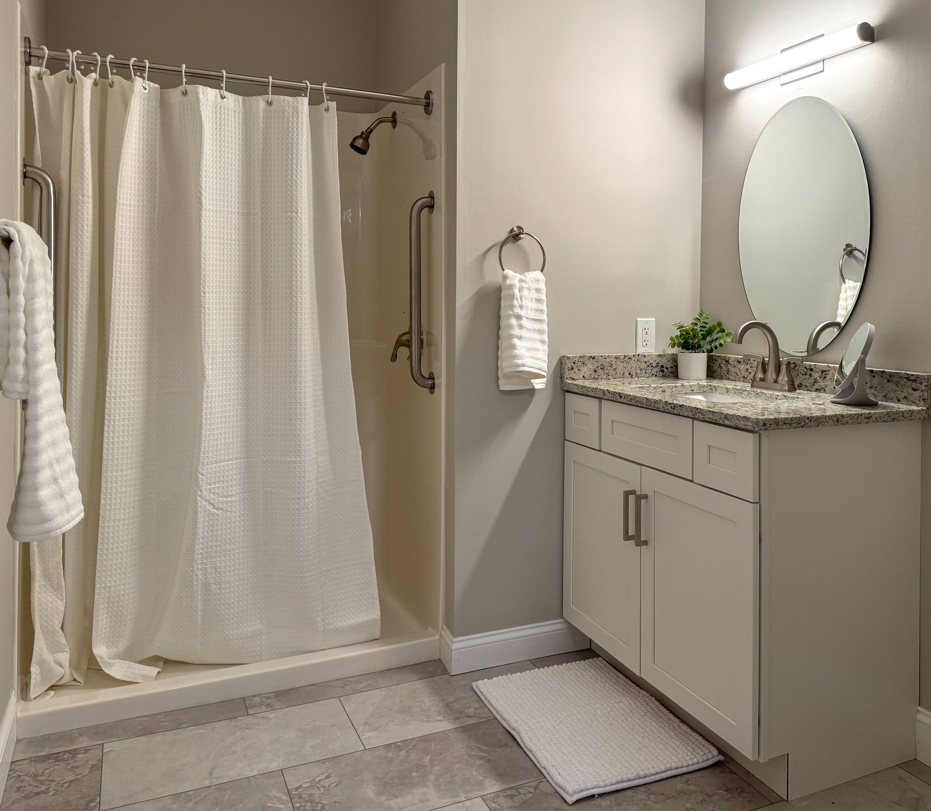 Bathroom with shower, vanity, and grab bars. Neutral tones, accessible design.
