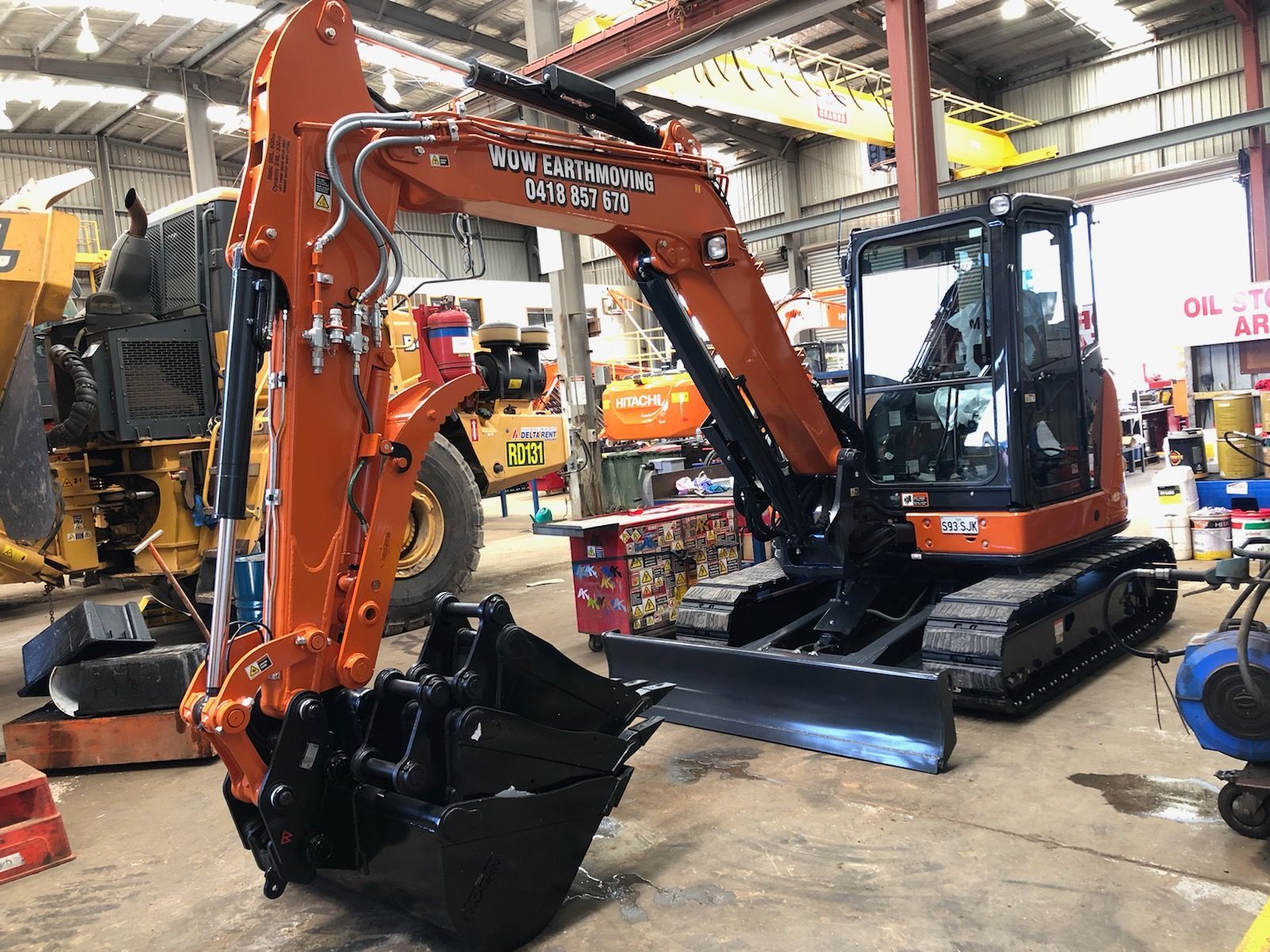 A large orange excavator is parked in a garage.
