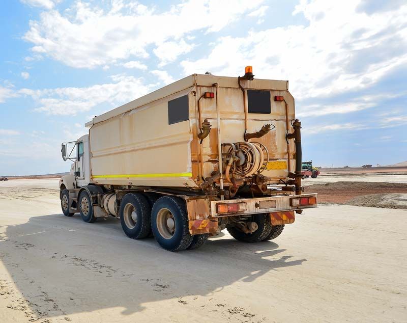 A large dump truck is parked on a dirt road.