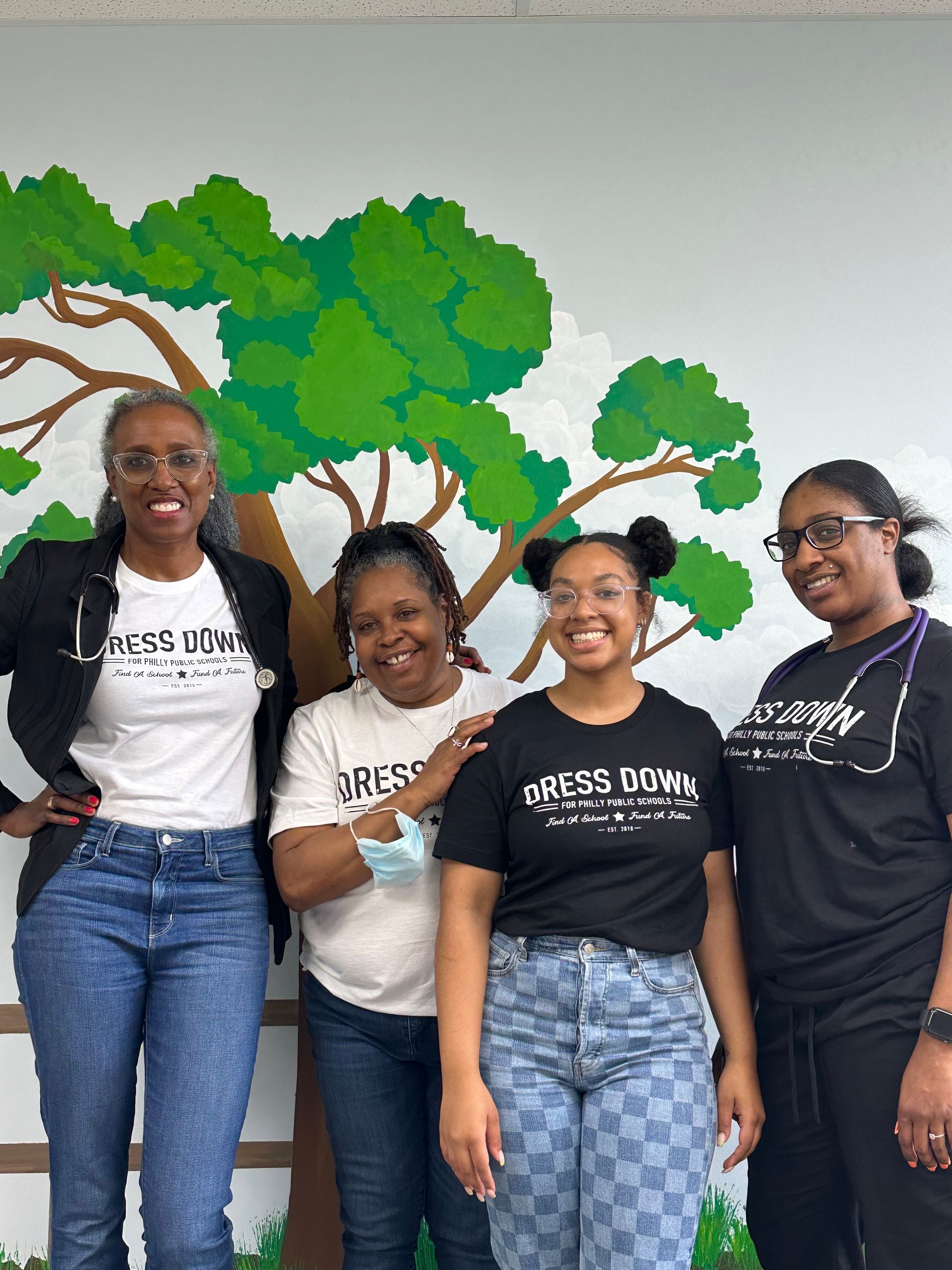The staff at Advocare Fairmount Pediatrics posing for a picture in front of a tree mural.