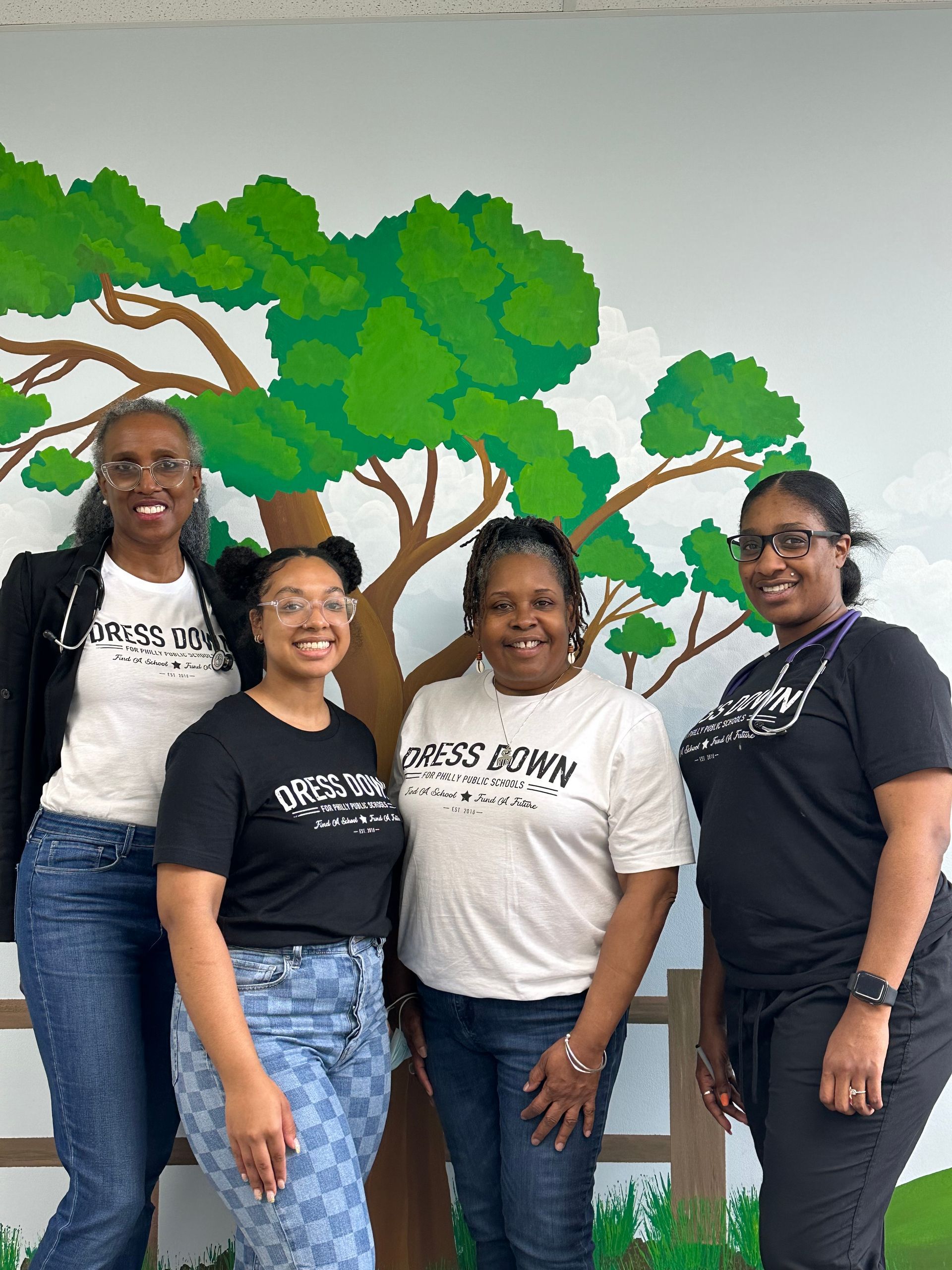 The staff at Advocare Fairmount Pediatrics posing for a picture in front of a tree mural.