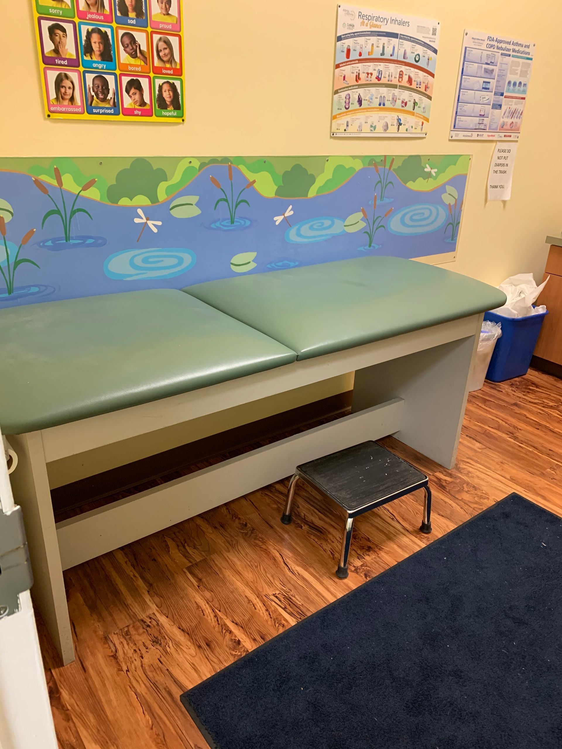 A doctor 's office with a green table and a step stool at Advocare Fairmount Pediatrics