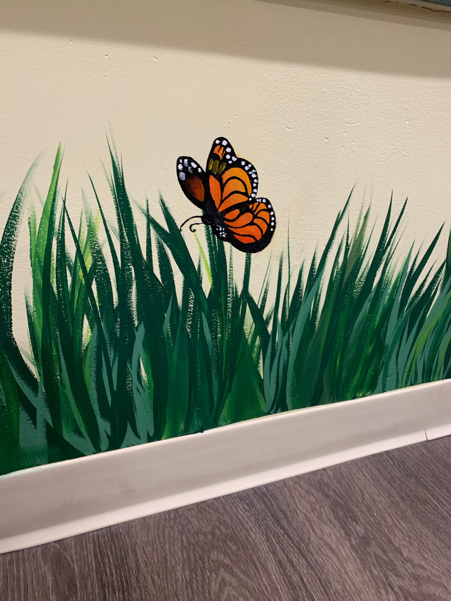 A painting of a butterfly in the grass on a wall at Advocare Fairmount Pediatrics