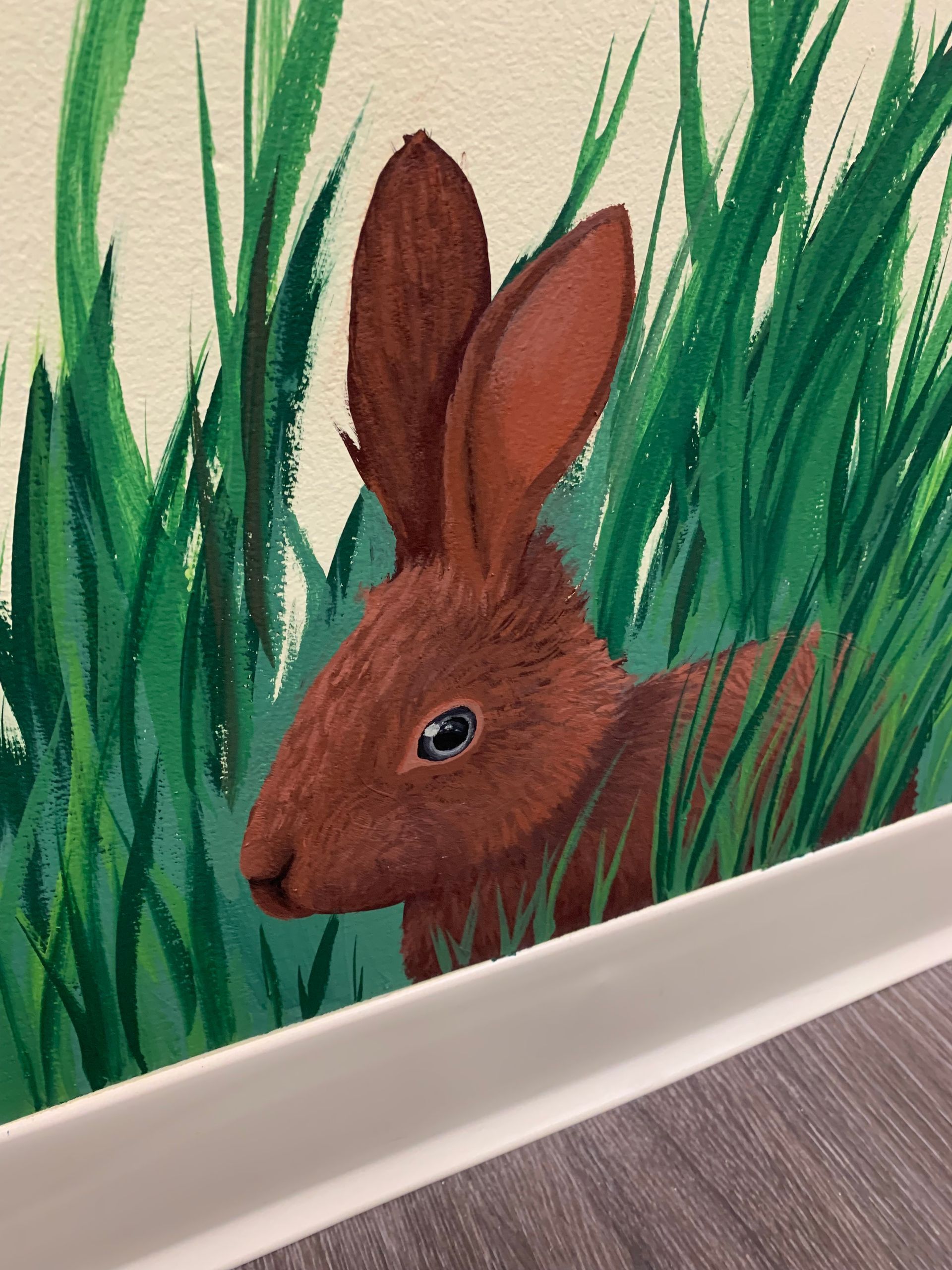 A painting of a rabbit peeking out of the grass at Advocare Fairmount Pediatrics