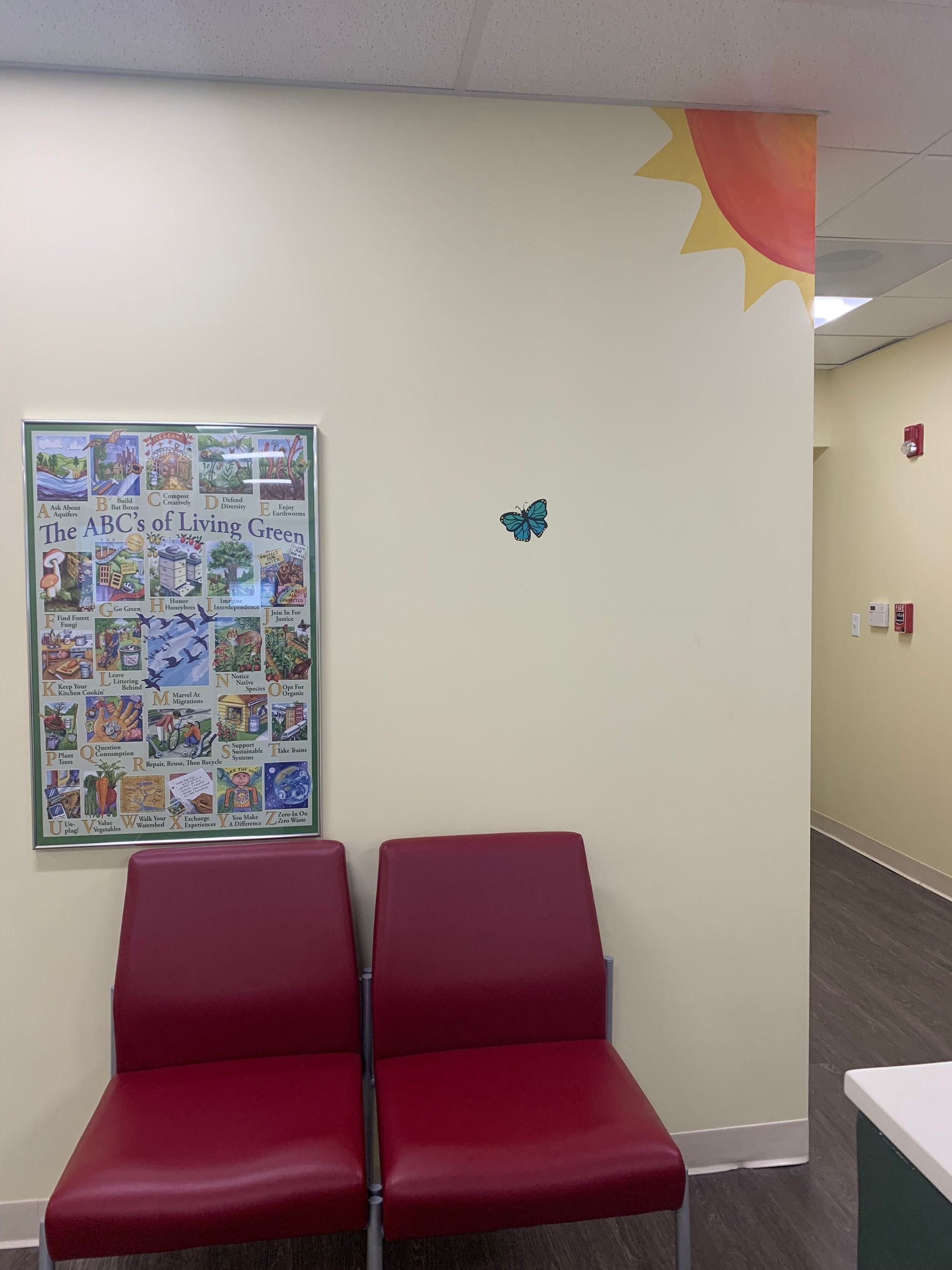 A waiting room with two red chairs and a poster on the wall at Advocare Fairmount Pediatrics