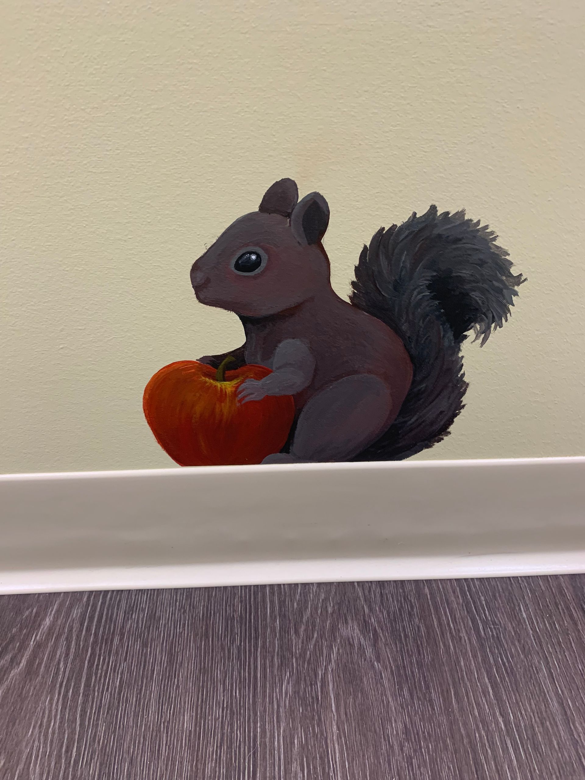 A painting of a squirrel sitting on a ledge holding an apple at Advocare Fairmount Pediatrics