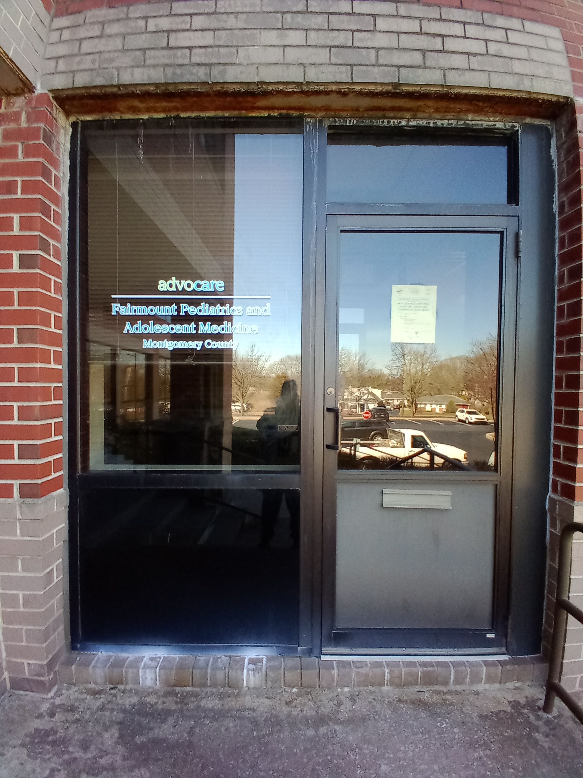 A brick building with a glass door that says Advocare Fairmount Pediatrics