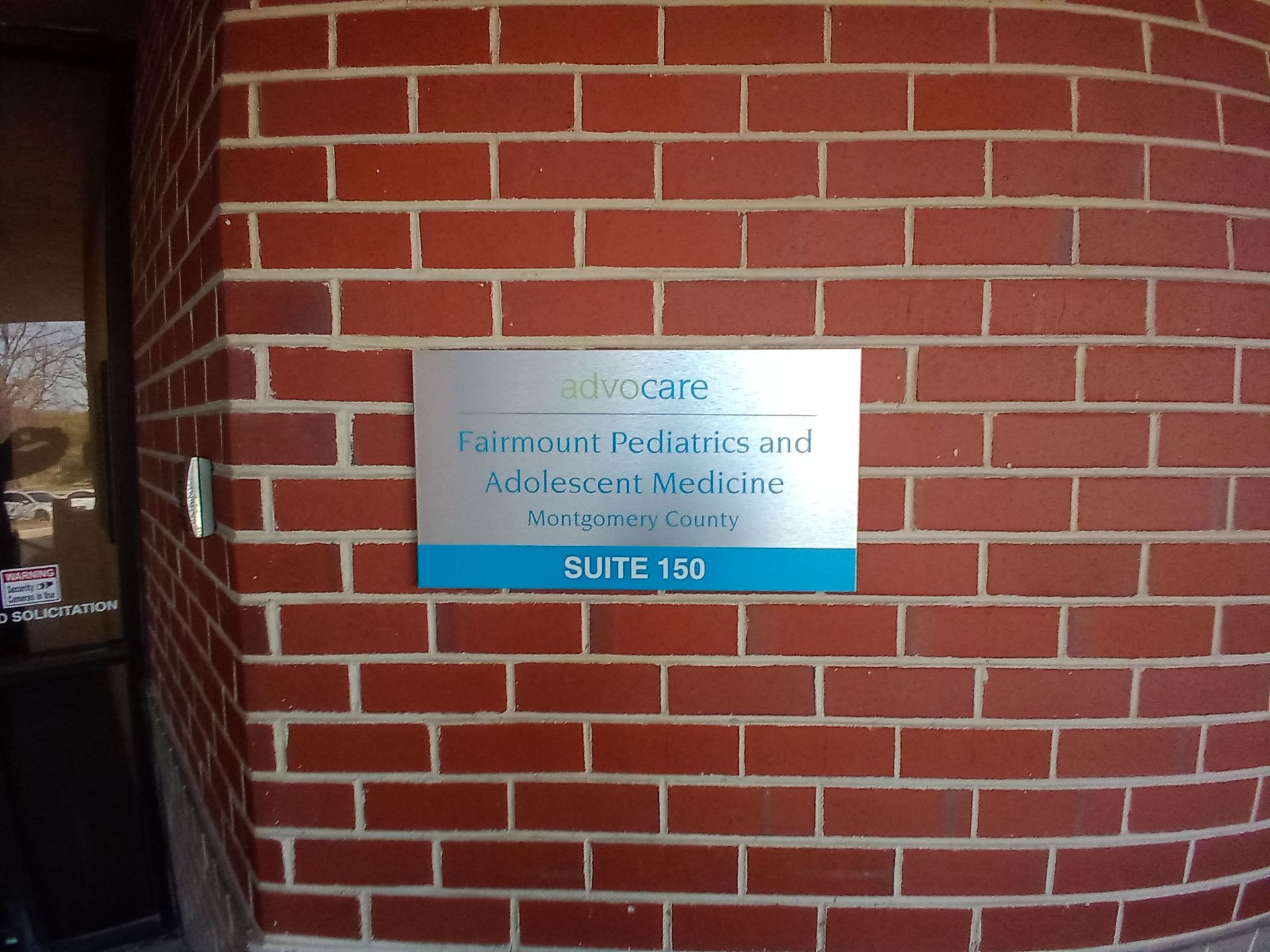 A sign on a brick wall says Advocare Fairmount Pediatrics