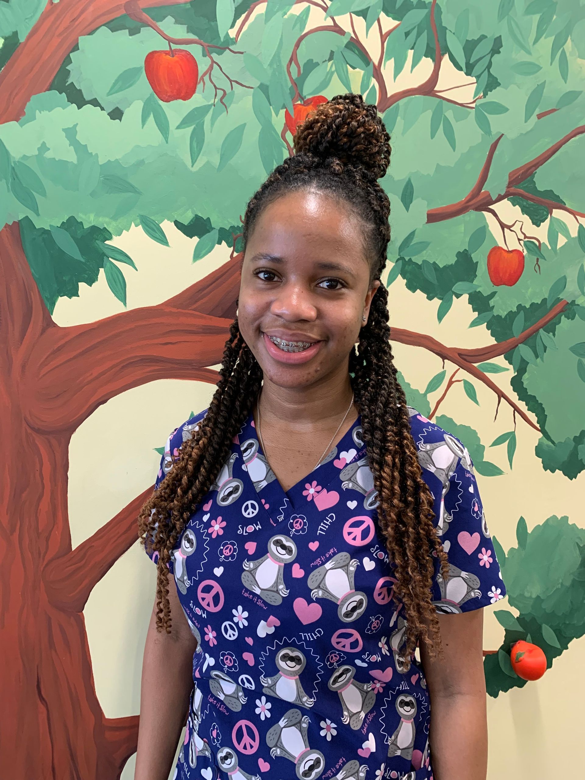 A nurse at Advocare Fairmount Pediatrics is standing in front of a painting of an apple tree.