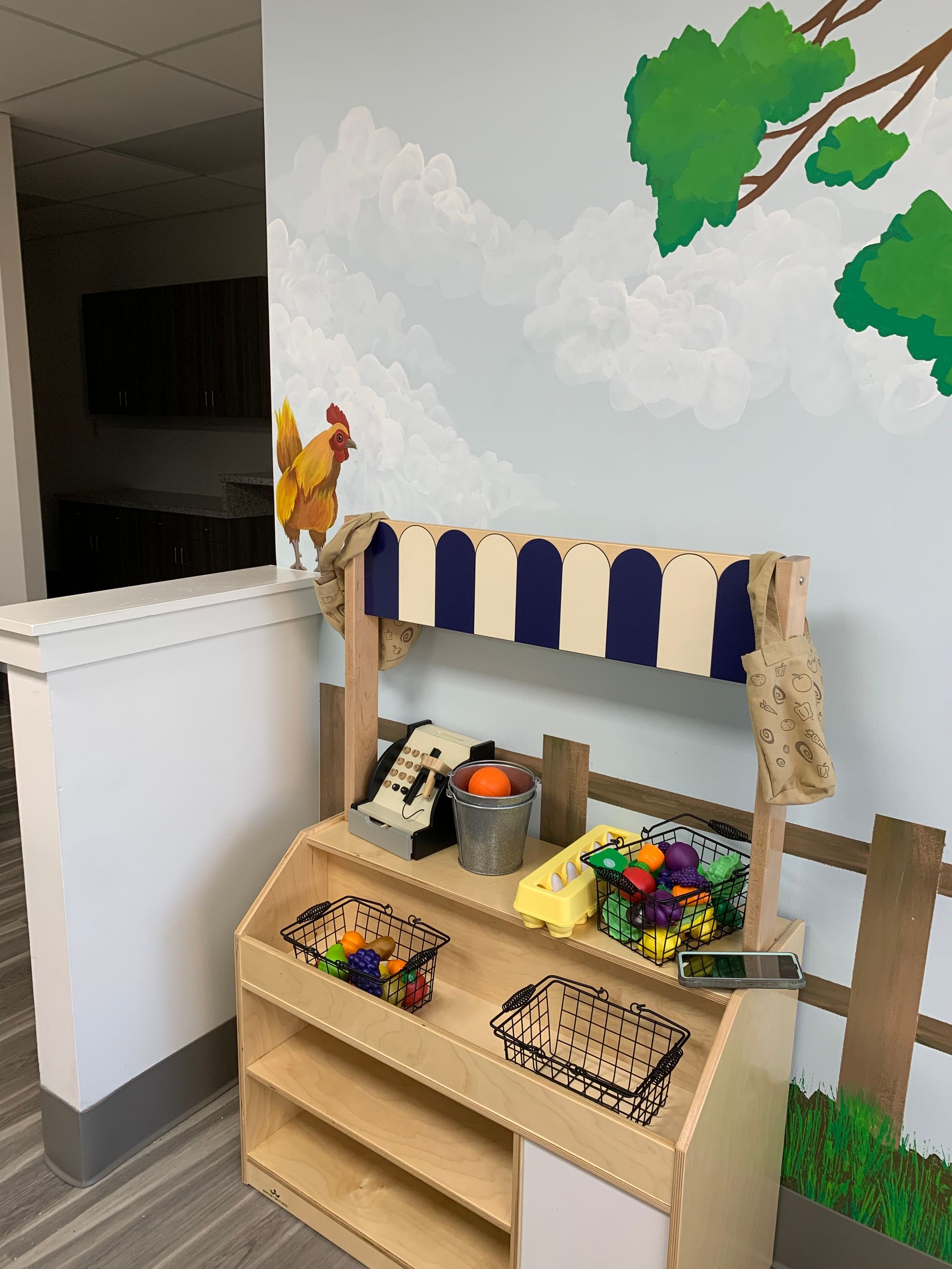 A wooden toy produce stand with a rooster on top of it at Advocare Fairmount Pediatrics