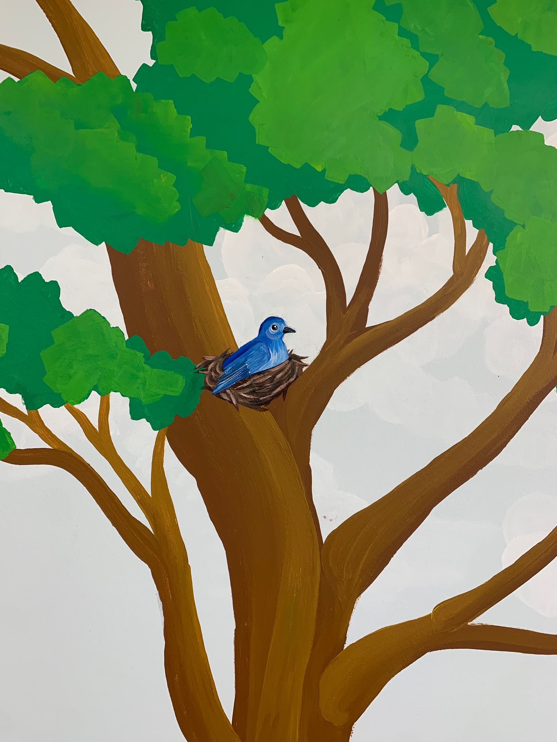A painting of a blue bird is sitting in a nest on a tree branch at Advocare Fairmount Pediatrics