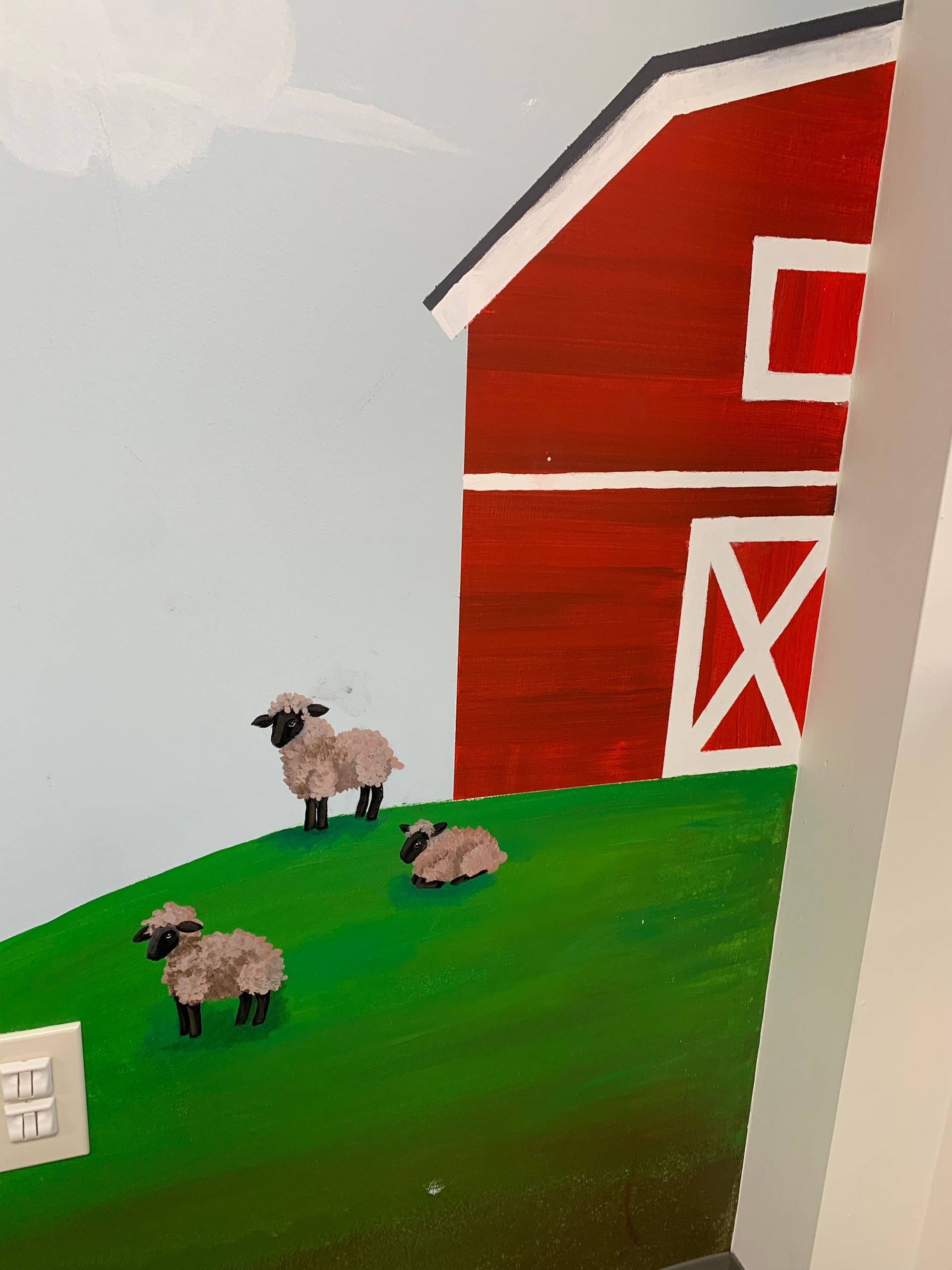 A painting of three sheep standing in front of a red barn at Advocare Fairmount Pediatrics