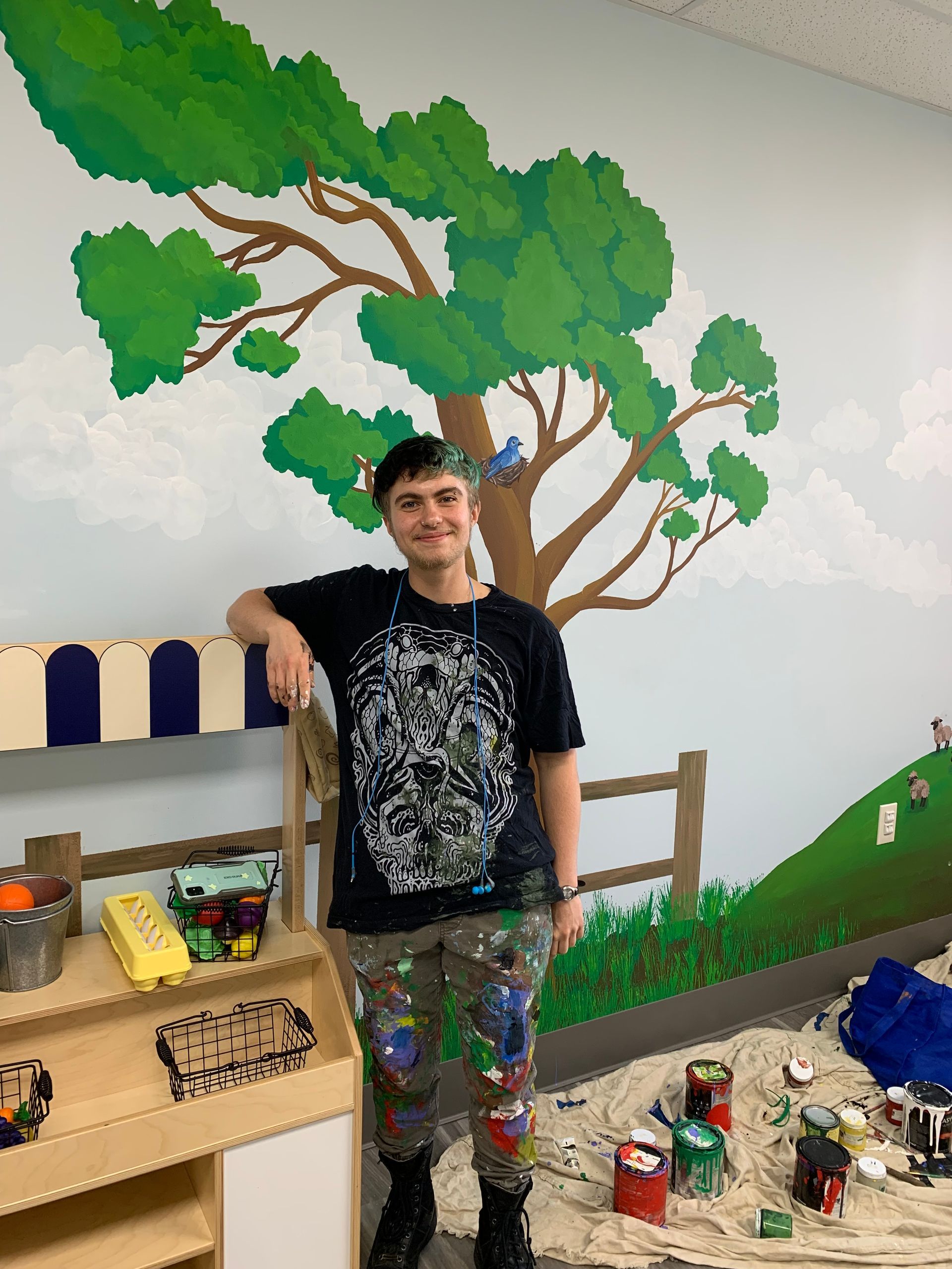A man is standing in front of a painting of a tree on a wall at Advocare Fairmount Pediatrics