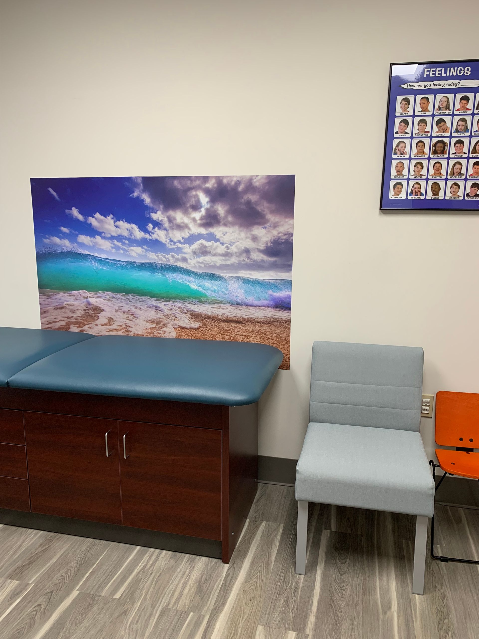 A room with two chairs and a table with a picture of a beach on the wall at at Advocare Fairmount Pediatrics