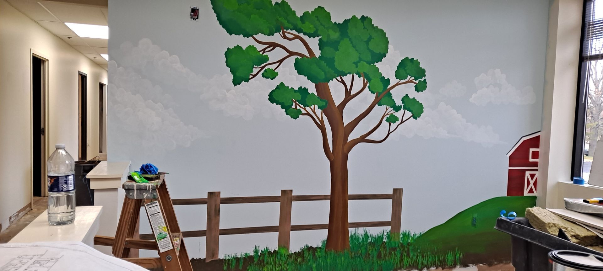 A wall with a painting of a tree and a barn on it at Advocare Fairmount Pediatrics