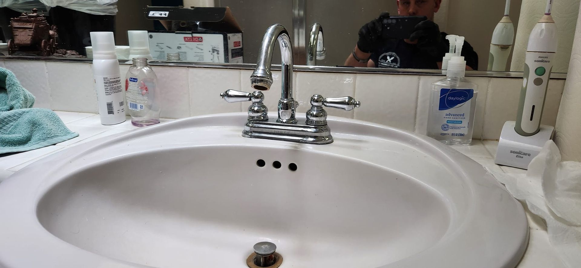A bathroom sink with a chrome faucet and various toiletries arranged on the countertop.