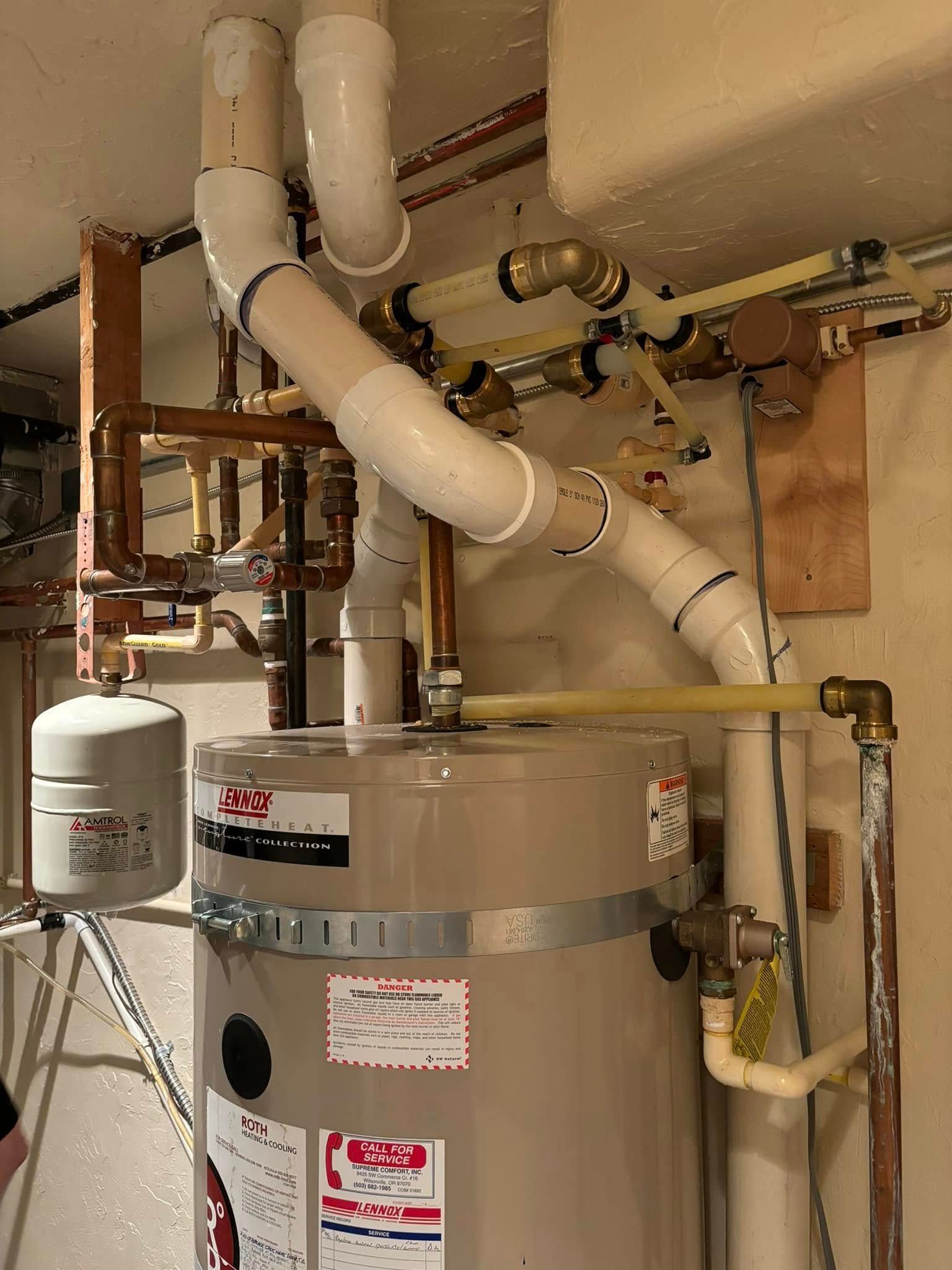 A gray water heater unit connected to complex white PVC exhaust piping and copper plumbing in a utility space.