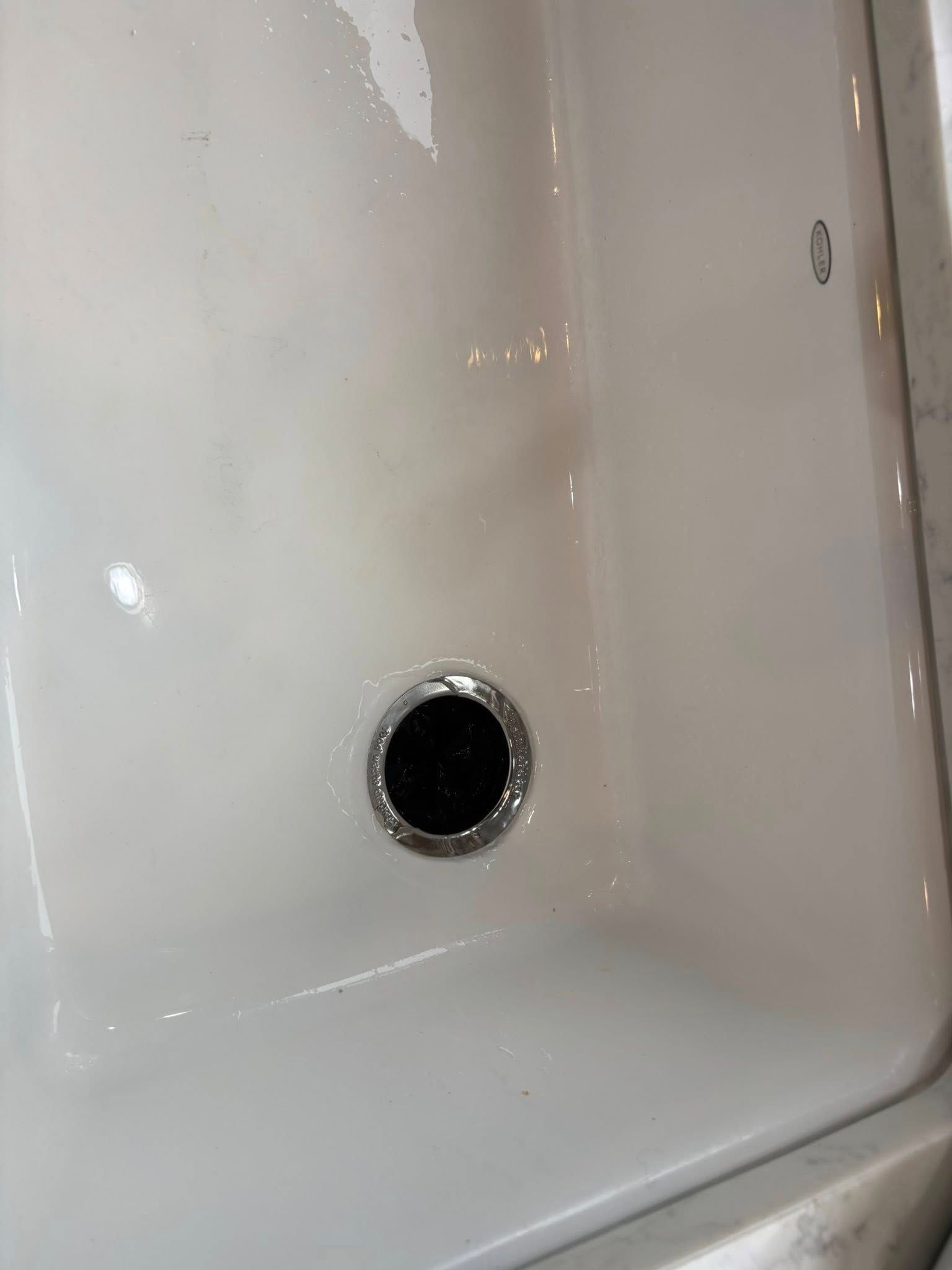 A white ceramic bathroom sink basin featuring a silver-rimmed drain.