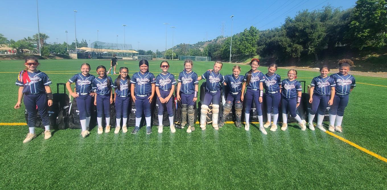 Youth soccer team lined up on a sunny field with a blue sky behind them