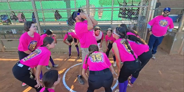 Players in bright pink shirts crouch around a court circle during a group game.