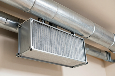 Ceiling-mounted HVAC filter unit with metal ductwork in an indoor room