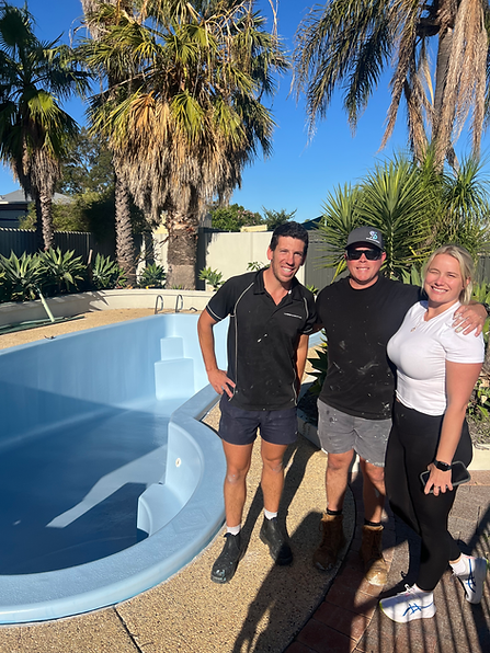 Three people standing by a pool on a sunny patio with palm trees in the background