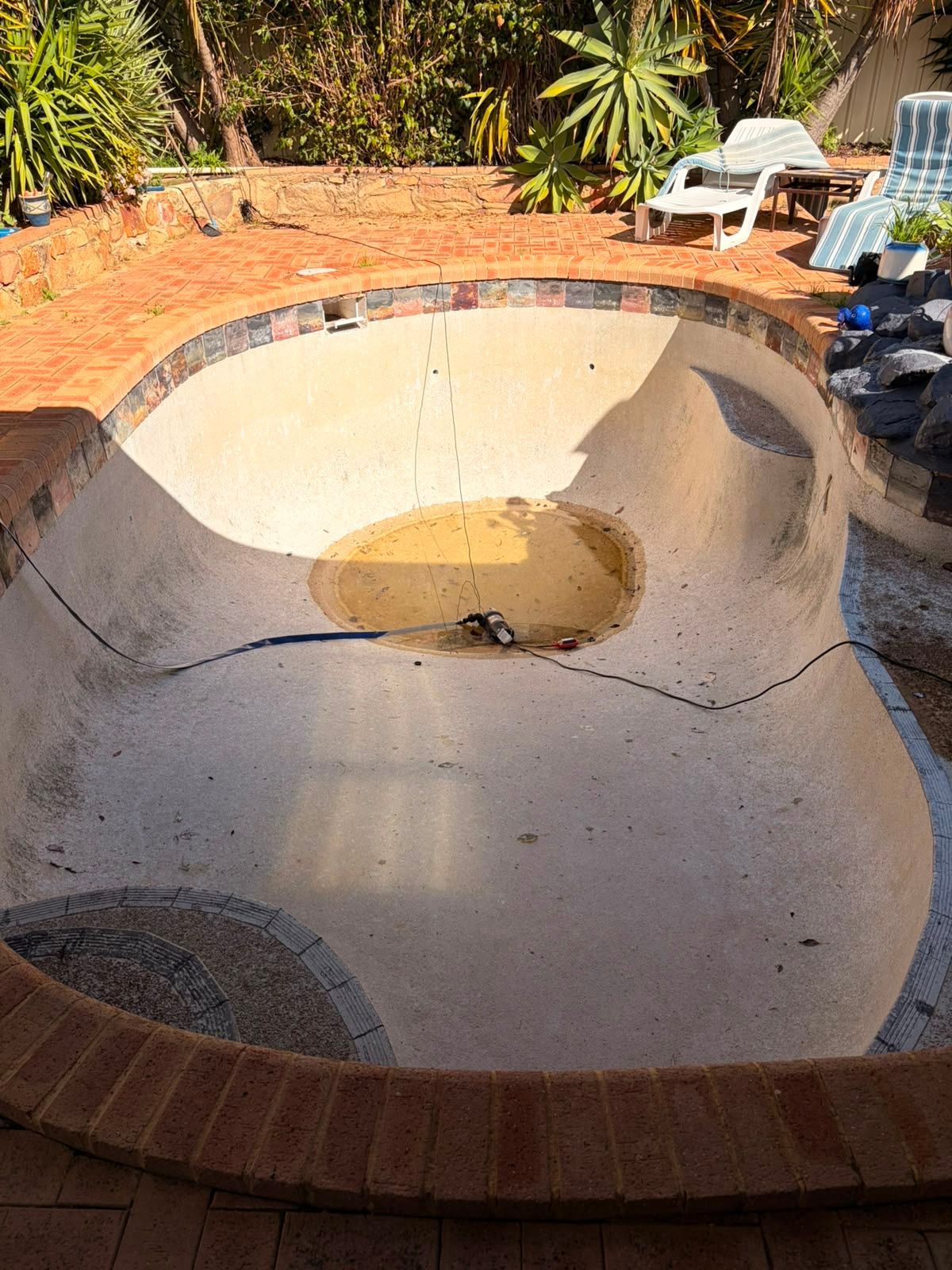 Before image of a swimming pool which requires resurfacing.
