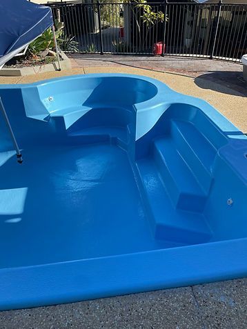 Blue empty backyard pool with built-in steps and seating area