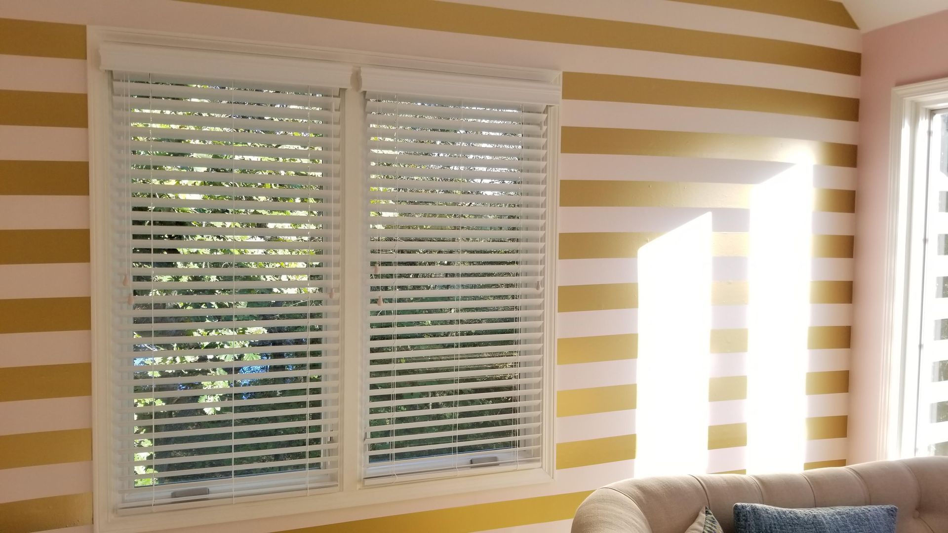 A living room with striped walls and blinds on the windows