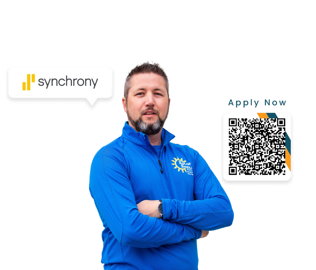 A man in a blue shirt is standing in front of a sign that says synchrony