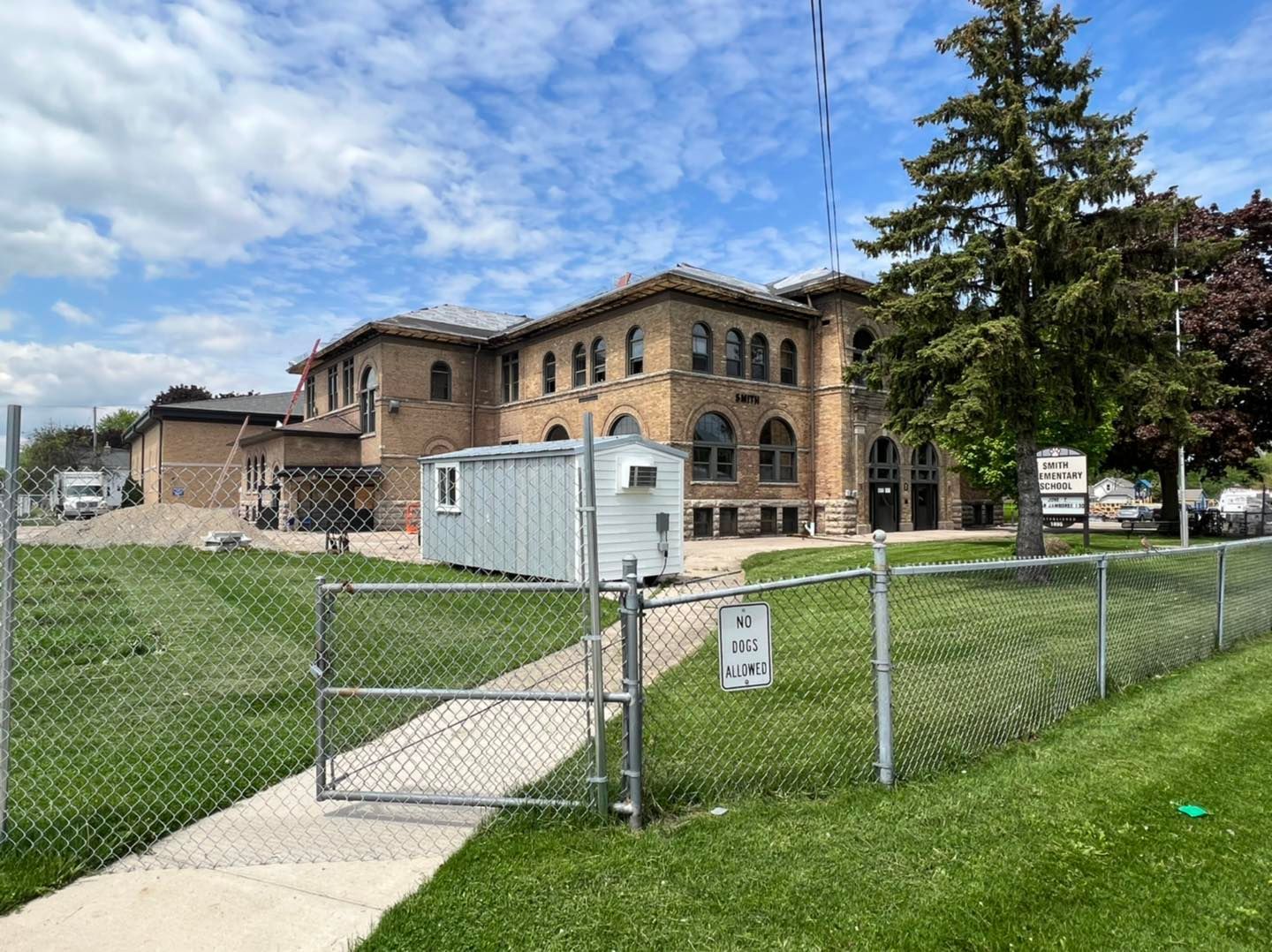 A large brick building is behind a chain link fence.