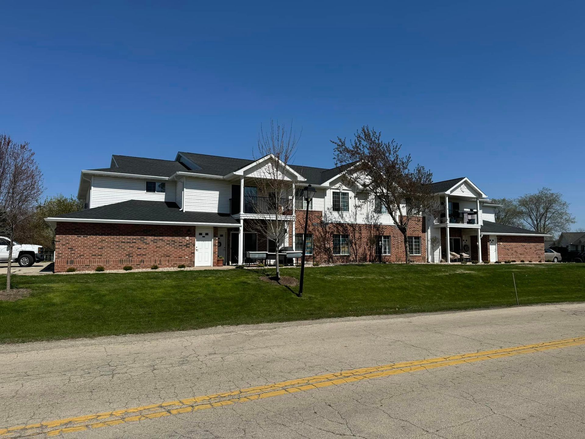 A two-story building with a brick lower level and white upper level, surrounded by a lawn under a clear blue sky.