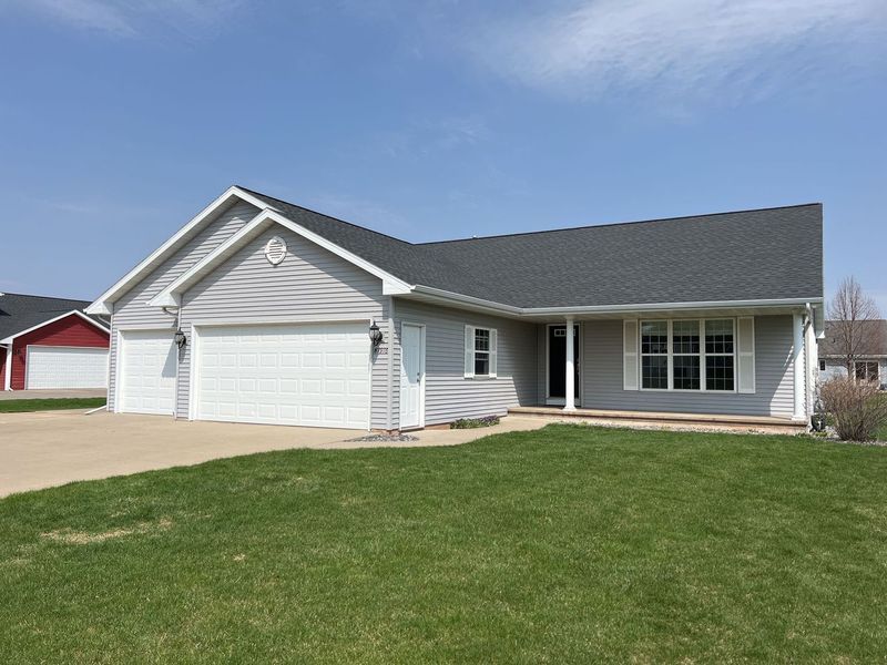 A single-story gray house with a two-car garage, white trim, and a small front lawn under a clear blue sky.