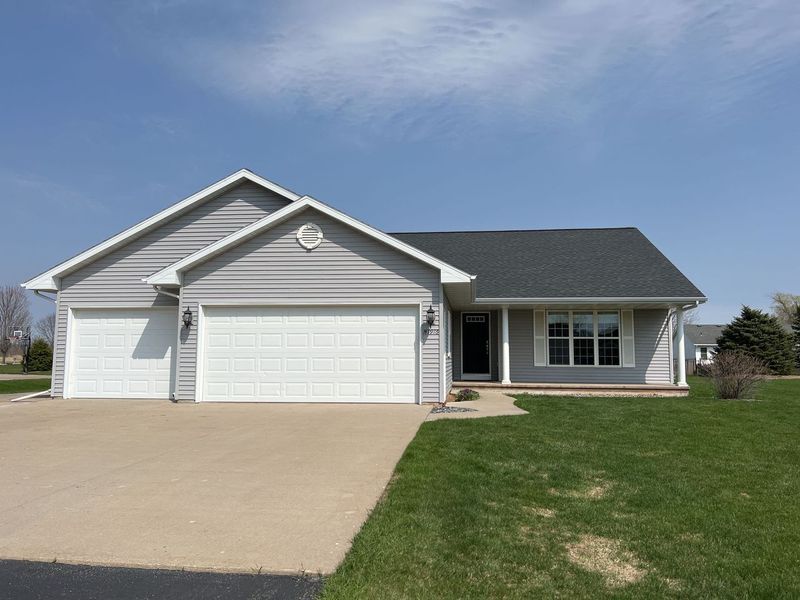 A one-story gray house with a two-car garage, white trim, and a small front porch under a clear blue sky.