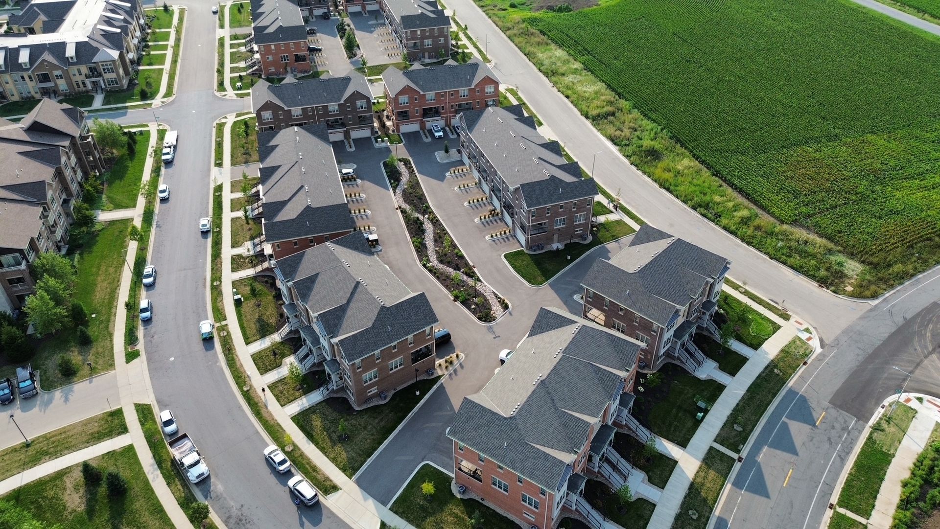 Aerial view of a residential neighborhood with brick houses, curved streets, and green lawns.