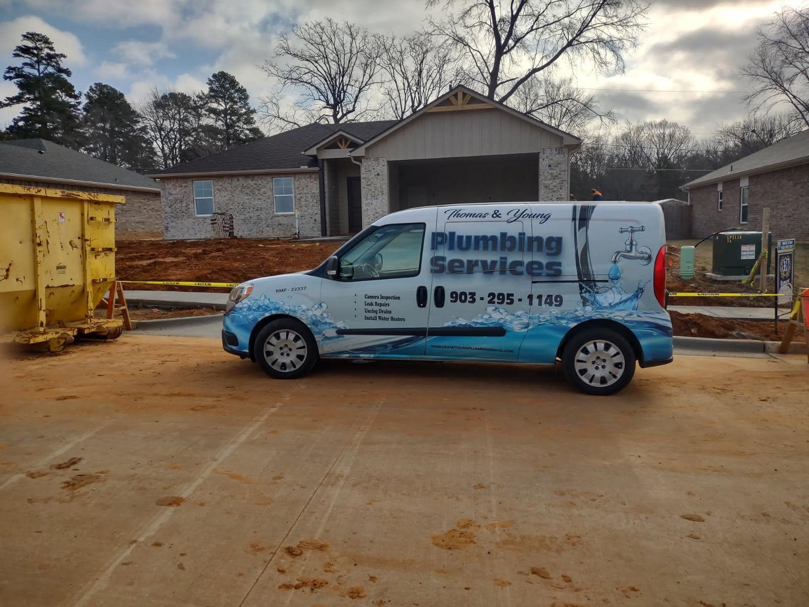 Plumbing services van parked on a construction site with a house in the background.