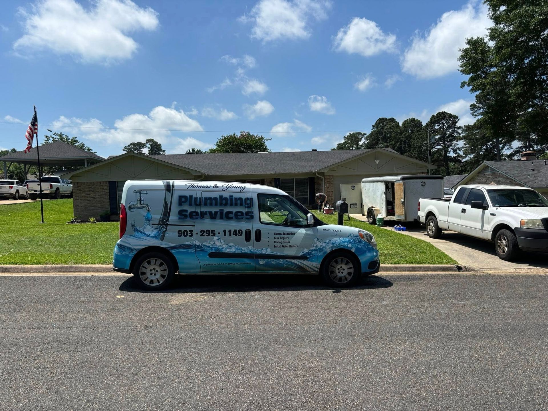 A plumbing services van parked in front of a house on a sunny day.