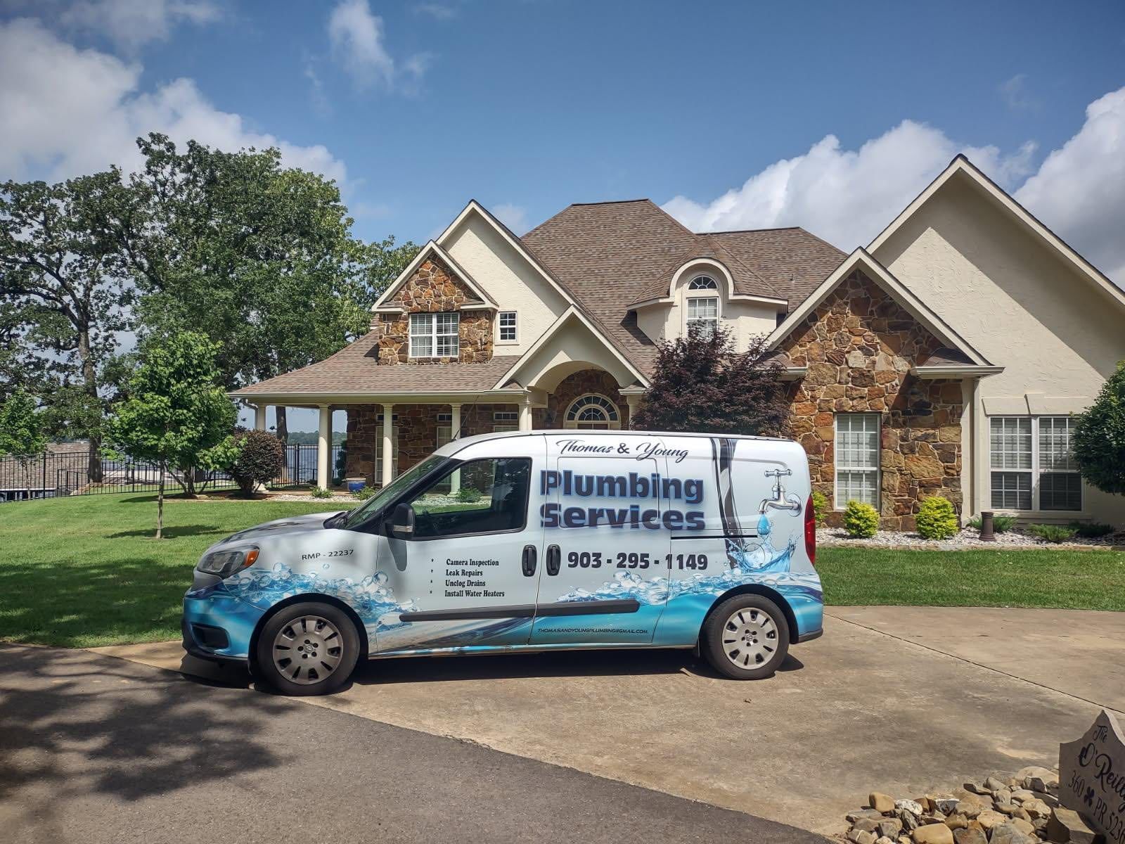 A plumbing service van parked in front of a two-story house on a sunny day.