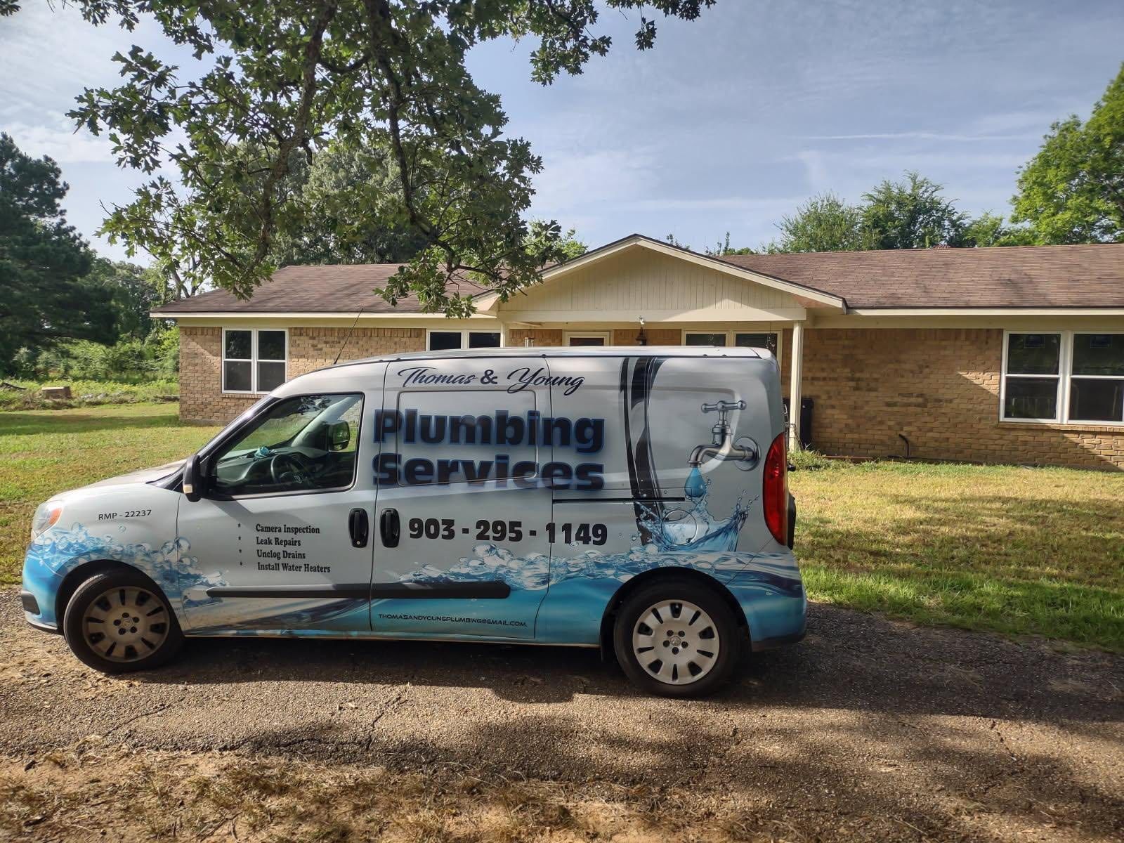 A plumbing service van parked in front of a house. The van has the company's logo and contact information.