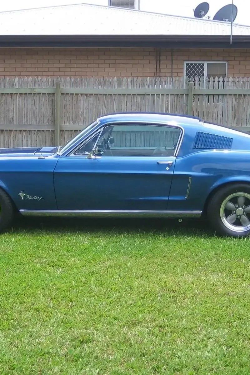A Blue Mustang is Parked in the Grass in Front of a House — Ace Exhaust Centre in Berserker, QLD