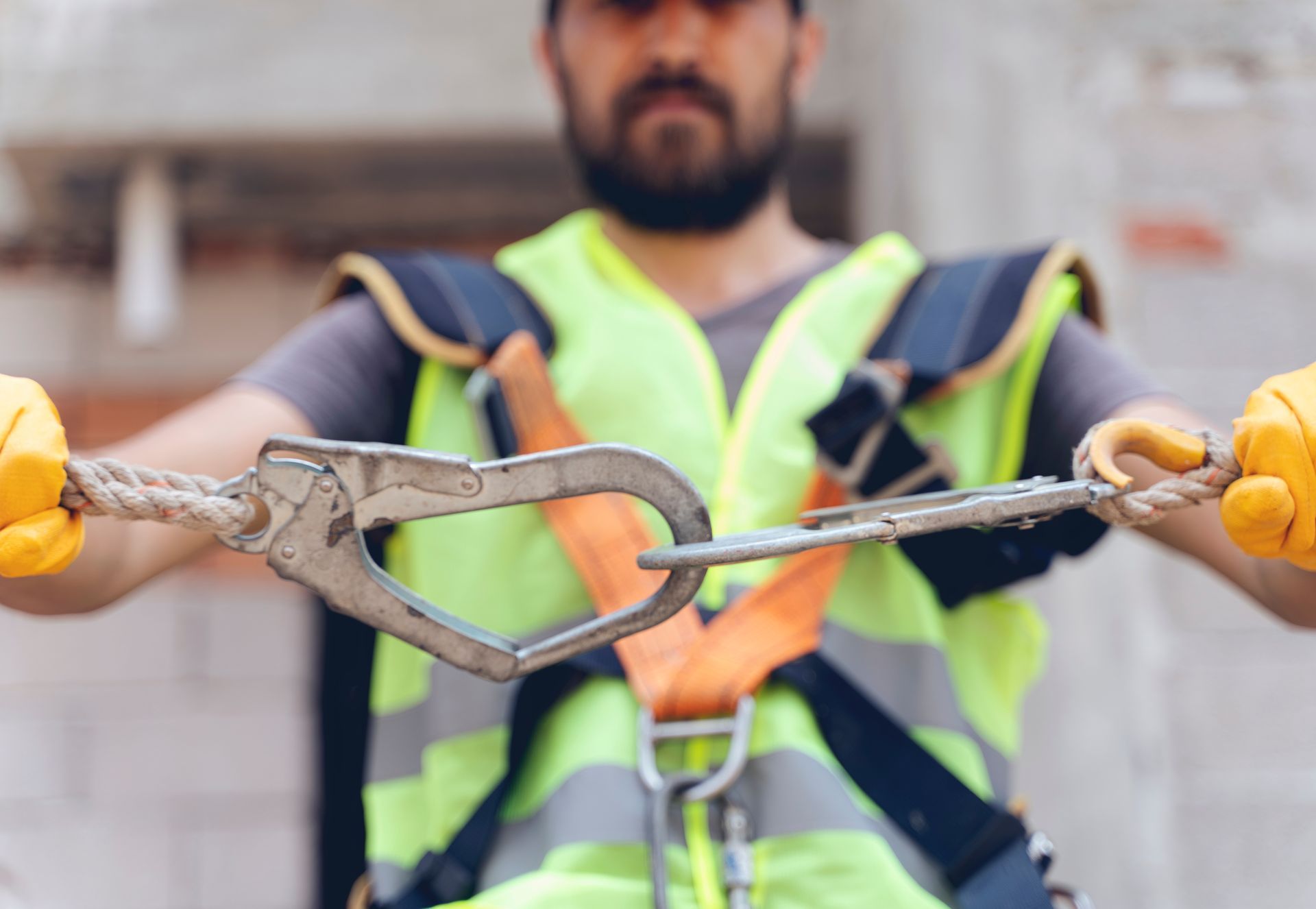 Obrero de la construcción con chaleco y arnés de seguridad, conectando un mosquetón.