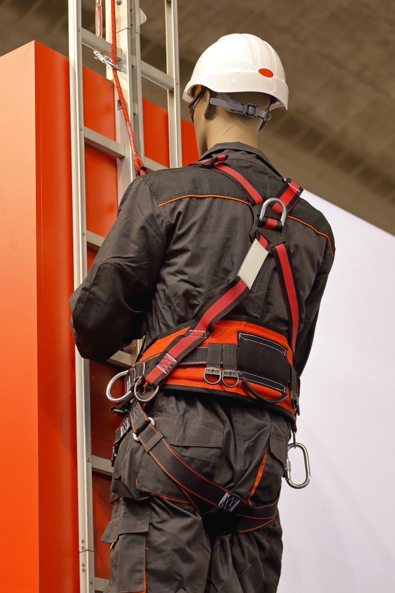 Maniquí con arnés y casco de seguridad, subiendo una escalera.