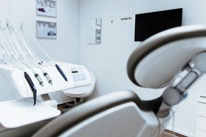 Bright dental clinic with white chairs, equipment, and a wall-mounted screen