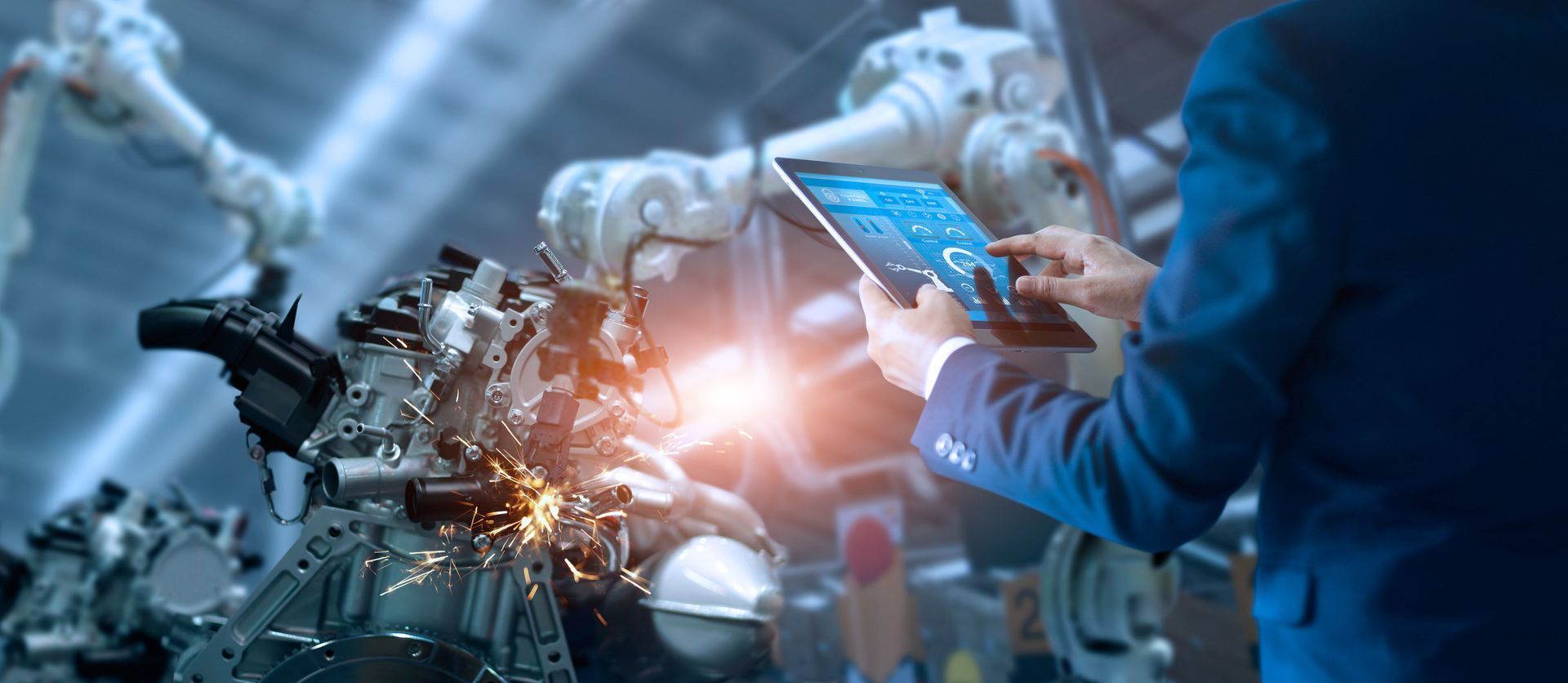 Technician using a tablet beside a robotic arm in a futuristic factory, with sparks and blue lighting